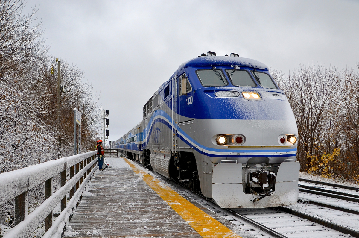 Montreal got its first snowfall of the winter this morning and the trees and the train are covered in sticky snow as AMT 86 arrives at Lasalle Station. In the background a crew takes a break from clearing the station platform as the train passes.