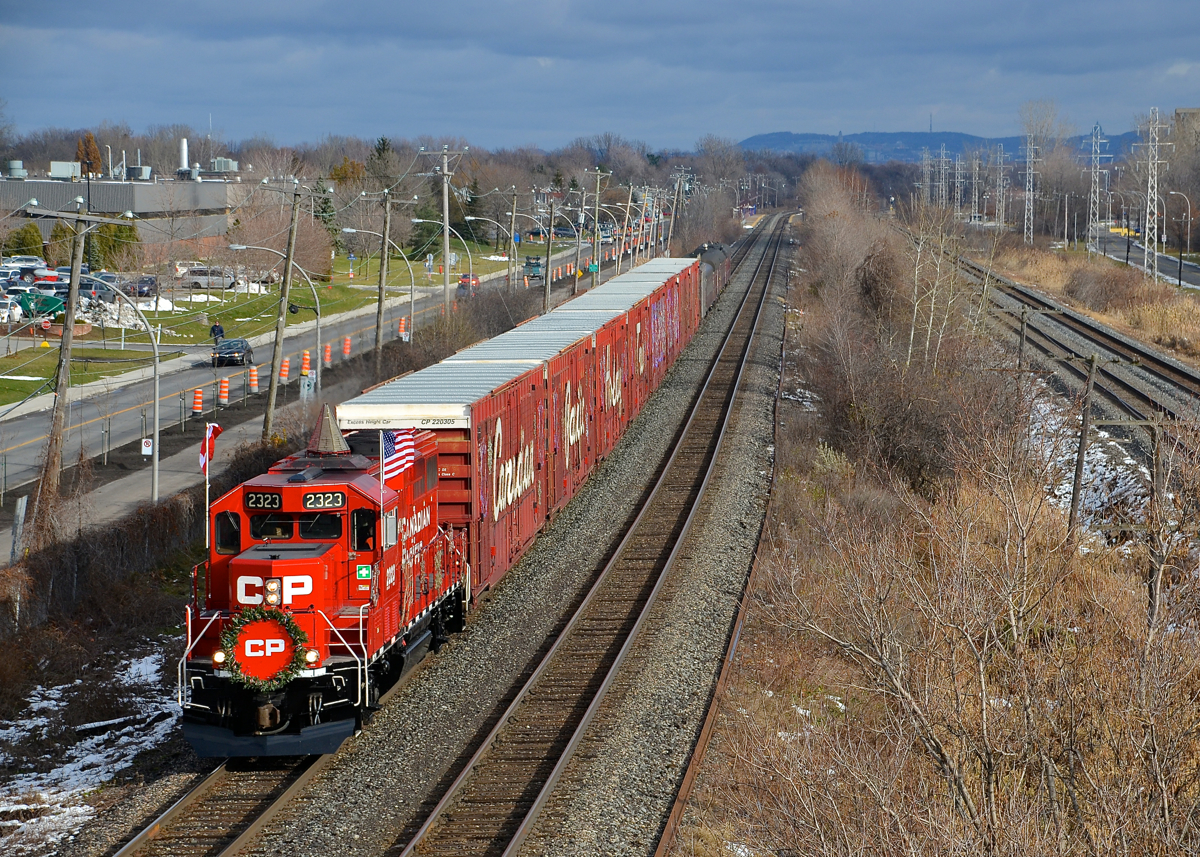 I got lucky twice over in catching the CP Holiday Train this afternoon, as I barely beat it to the St-Jean overpass in Pointe-Claire and I got a few minutes of sun during a mostly cloudy day. Here it is seen heading for shows in Ontario this afternoon, with CP 2323 leading a 62-car axle train. Up ahead are stops in Finch, Merrickville, Smiths Falls and Perth.