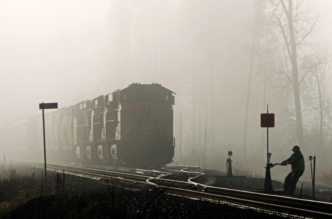 The morning sun is doing it's best to overpower the thick fog lingering over Swansea Siding as a conductor "bend's the iron" at the east switch.