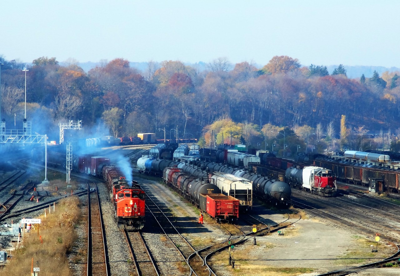 CN 4770 with CN 4785 and CN 4776 creates a little more haze in the Hamilton Basin as it approaches MM 39 in the Stuart Street Yard. NECR 3840 is busy doing switching duties and will soon add several cars to the consist before they depart.