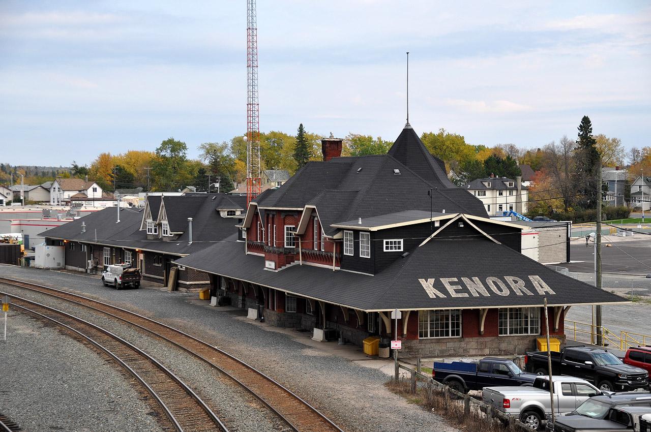 It is great that the Kenora CP station complex has been designated 'Heritage',(1991) as it is a beautiful sight. This view was taken from the Matheson St overpass at the west end of the yard. Kenora station was constructed back in 1899. The left foreground, a parking area for staffers and employees, was once a beautiful garden, complete with lush grasses and endless flowers. The idea was for new Canadians heading west to start a new life would see the beauty at station stops and give them encouragement for what lied ahead. Boy were they in for a surprise!!! There was no beauty in landing somewhere in Saskatchewan or Southern Alberta and fending oneself against a prairie winter. Many newbies stuck it out though, and as the years passed the railroads, as the major highways in the east, cut back on "beauty" as a non-contributor to the bottom line and neglect took over.