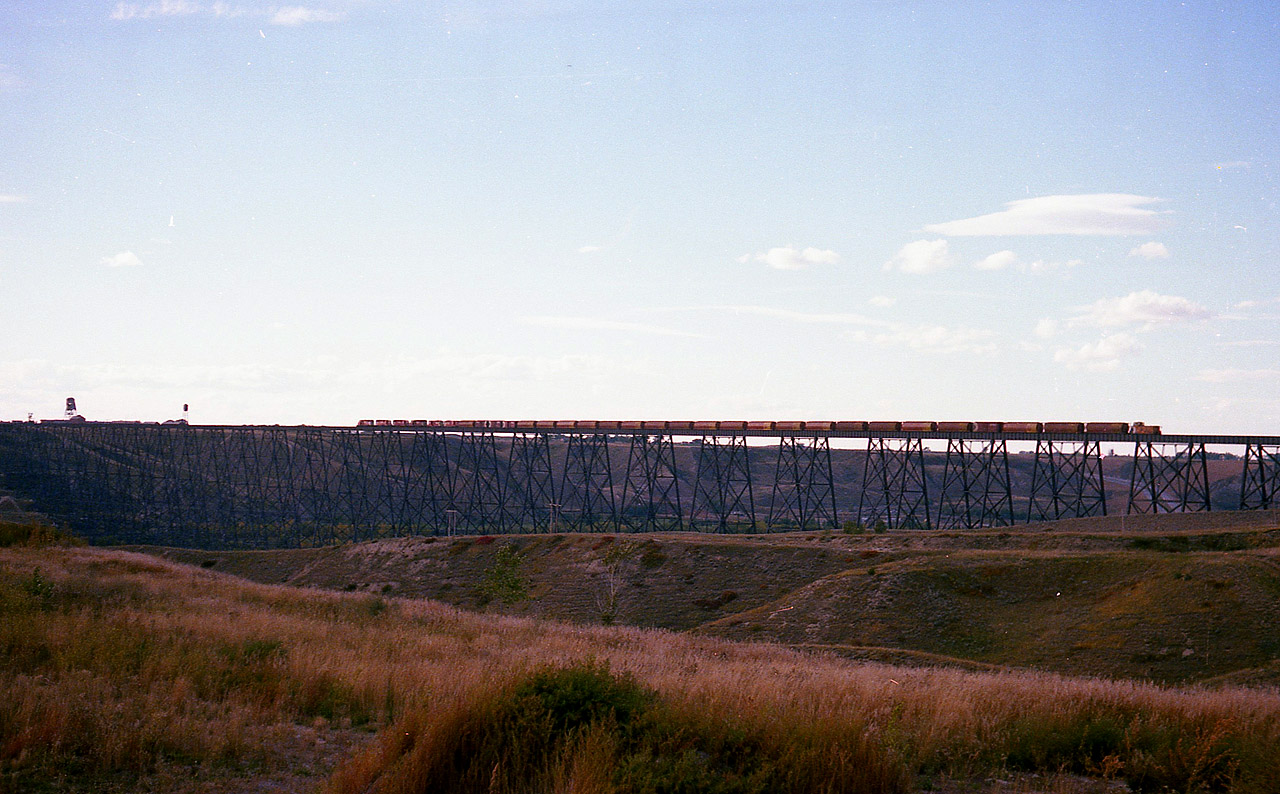 This bridge is of such massive proportions it just seems to swallow up a 6 unit, 30-40 car train like it was an N scale on an HO layout. Just to the west of Lethbridge, it spans the Oldman River and Valley to the tune of 5,327 feet, and at its highest point 314 ft above the valley floor. Even if this is a westbound train, complete with caboose, it made for a spectacular sight to witness. All six units up front are SDs.