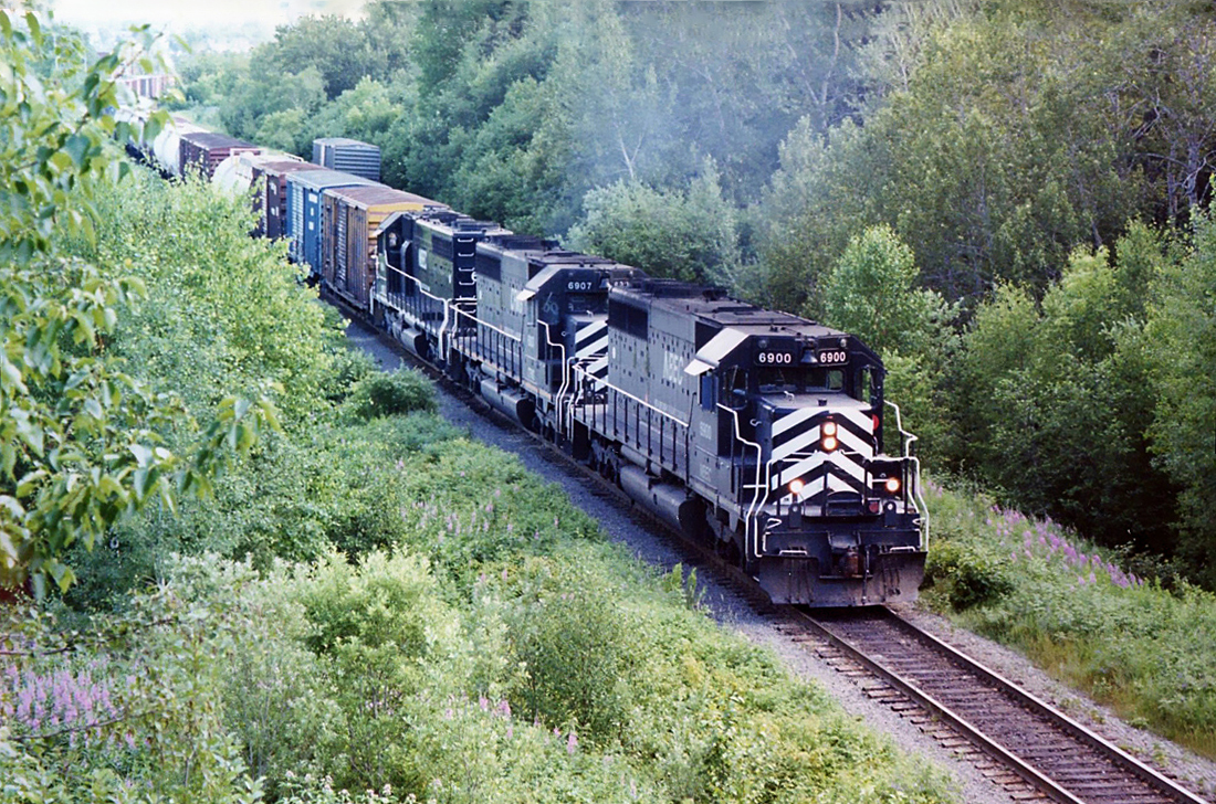 Northbound New Brunswick East Coast freight with in the lead GMD SD40 6900, CFMG SD40  6907 and NBEC SD40  6905 leaving Bathurst, N.B. July 17, 2004.