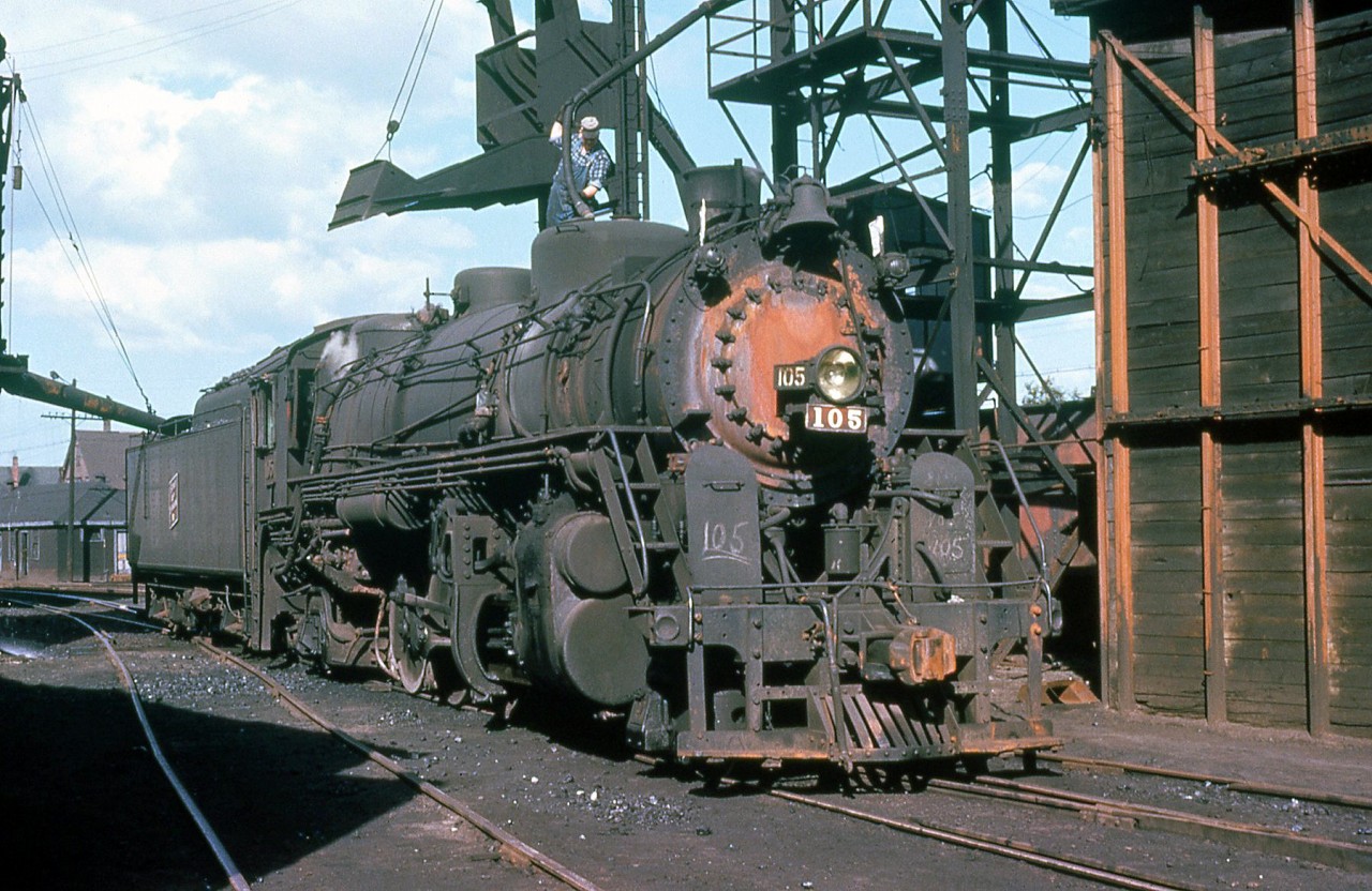 Sydney and Louisburg Railway 2-8-2 105 is pictured at Sydney in 1961, with an employee perched on top filling 105's sand dome from the nearby sand tower. S&L 105 was originally built for the Detroit and Toledo Shore Line as their 32 by Lima Locomotive Works in 1936, acquired by the S&L in 1954 and renumbered to 105. The coal-hauling road operated steam later than most and dieselized in the early 1960's, and as a result 105 was scrapped later that year in November 1961.(Original photographer George Schaller, duplicate slide from the collection of Bill Thomson).