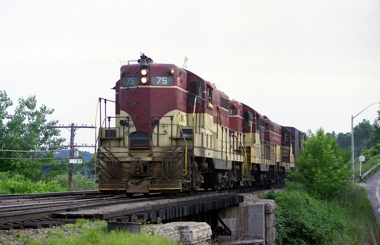 One can almost tell it is a hot, humid and hazy summer afternoon. TH&B 75, 403 and 76 power the Starlite from Aberdeen Yd in Hamilton back to Toronto; running a bit earlier than usual, giving plenty of light for a decent photo. The train is passing the Mile marker 37 at Bayview Jct., almost directly over top of the old Valley Inn Rd underpass. Times have changed.....the road is no longer open to vehicular traffic.
