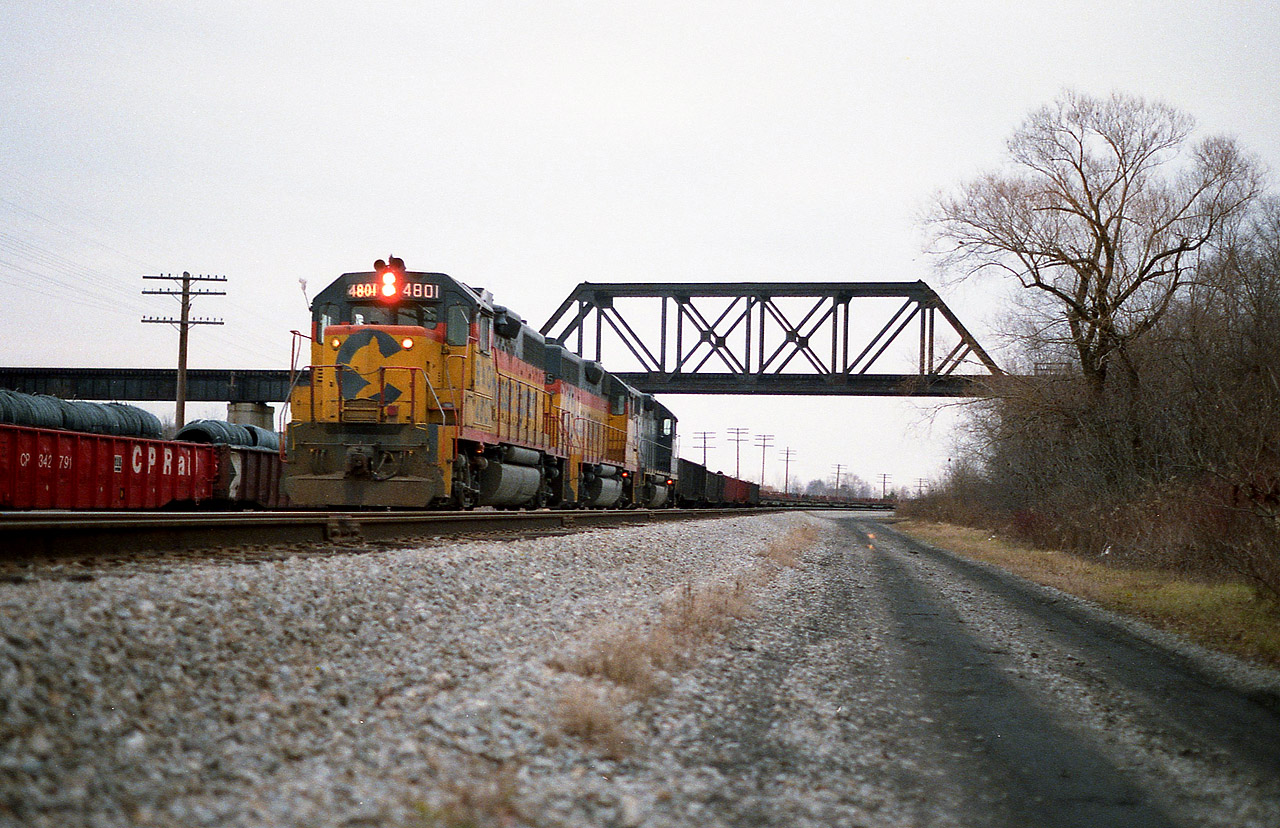 B&0 4801, C&0 3885 and C&0 4828, the power for this days "Nanticoke Steel Train", is shown here on the CP/TH&B STEEL train's first month of operation over the route south from Brantford. The high bridge in the photo is the old LE&NRR structure (Lake Erie & Northern). Because it is out of commission, TH&B was running the leased Chessie units down their old track, out the west end of their wye at Waterford, then backing down the CASO eastward, crossing over, and up the south side. (That connector is out of sight on the other side of the bridge on the right) and this enabled the train to continue on southward. The intricate manoeuvre was all because the bridge had been out of service for many years. CP eventually redecked the bridge but then the train was cancelled due to track washout in Brantford anyway. Currently it is used as part of the LE&N Hiking Trail. On this day I have forgotten why I was able to photograph this power moving lite. I assume cars were being set off or picked up, as there was room on the west wide of the wye for a dozen or so cars.