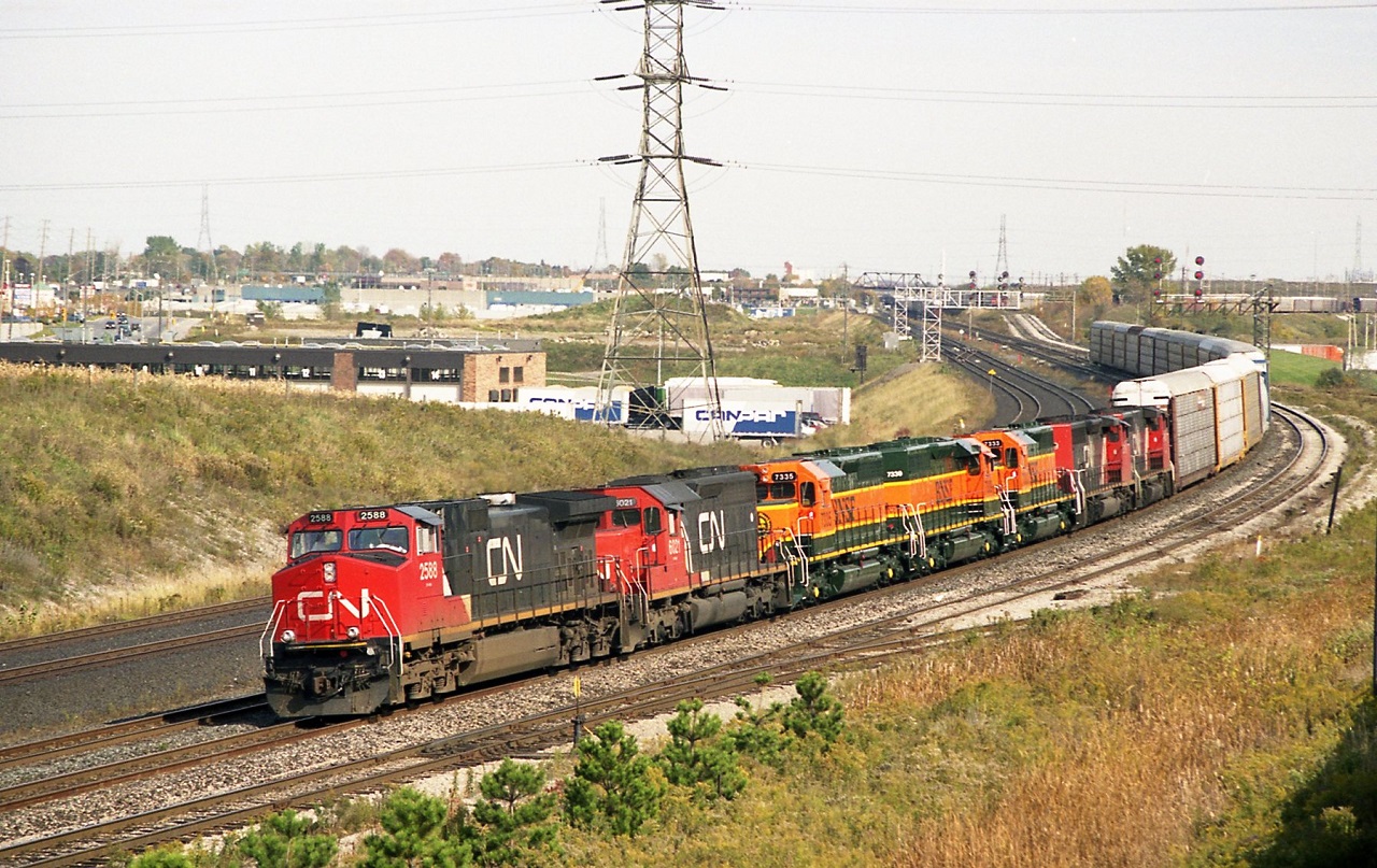 The Hopkins street over pass in Whitby has provided a good location and a variety of treasures over many years. On this fall day in October 1999 a CN west bound lifts cars from Oshawa yard. CN 2588 6021 BNSF  in transit 7335 7338 7333 and CN 5319 with another unidentified dash 2 provide the power. The BNSF SD40,s are ex CN units rebuilt in Montreal .