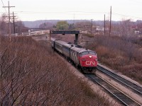 If it wasn't for that walkbridge in the background of this scene, the location might be hard to identify. That little shortcut is the walkway from Homestead Av to the Bruce Trail Headquarters in the Hamilton Botanical Gardens. I am standing on the side of the CP bridge over the CN Dundas looking toward Mile 1, and morning train #84 with CN 6519 on the lead, is coming at me under dangerously decrepit old Guelph Rd bridge, which was thankfully replaced many years ago. This miserable dull day was the first day of CP detours down from Guelph Jct after the famed Mississauga Wreck of Nov 1979. I was getting restless over the lack of hopeful traffic, and went for a walk, but keeping very close tabs on the CP.:o)