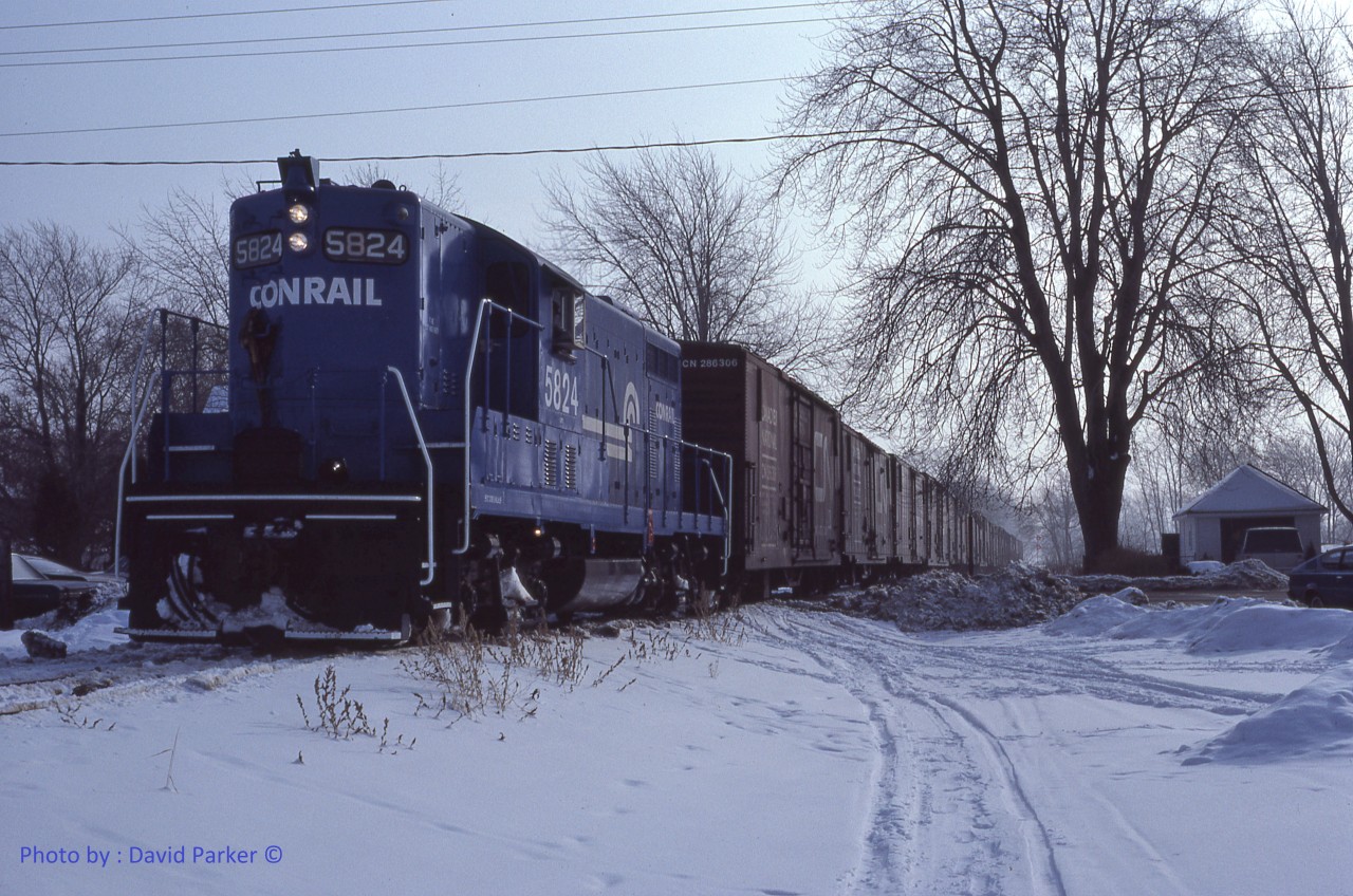 Conrail GP7 5824 leads the "Leamington Local" WQLE-1 out of Leamington, Ont on Jan 23rd 1981.  The train of CN Alcohol-heated insulated boxcars full of soup and ketchup from the Heinz plant has just crossed the C&O mainline on its slow speed journey up to Comber where it will be met by "The Plug", CR WQWI local from Windsor to St. Thomas.  The South end of the Leamington Branch was the Southernmost track in Canada. Both the Leamington Branch (Later owned by CN as the Leamington Sub) and the C&O (CSX) tracks through Leamington are all gone now. The ex NYC station still stands while the C&O depot burned down several years ago.