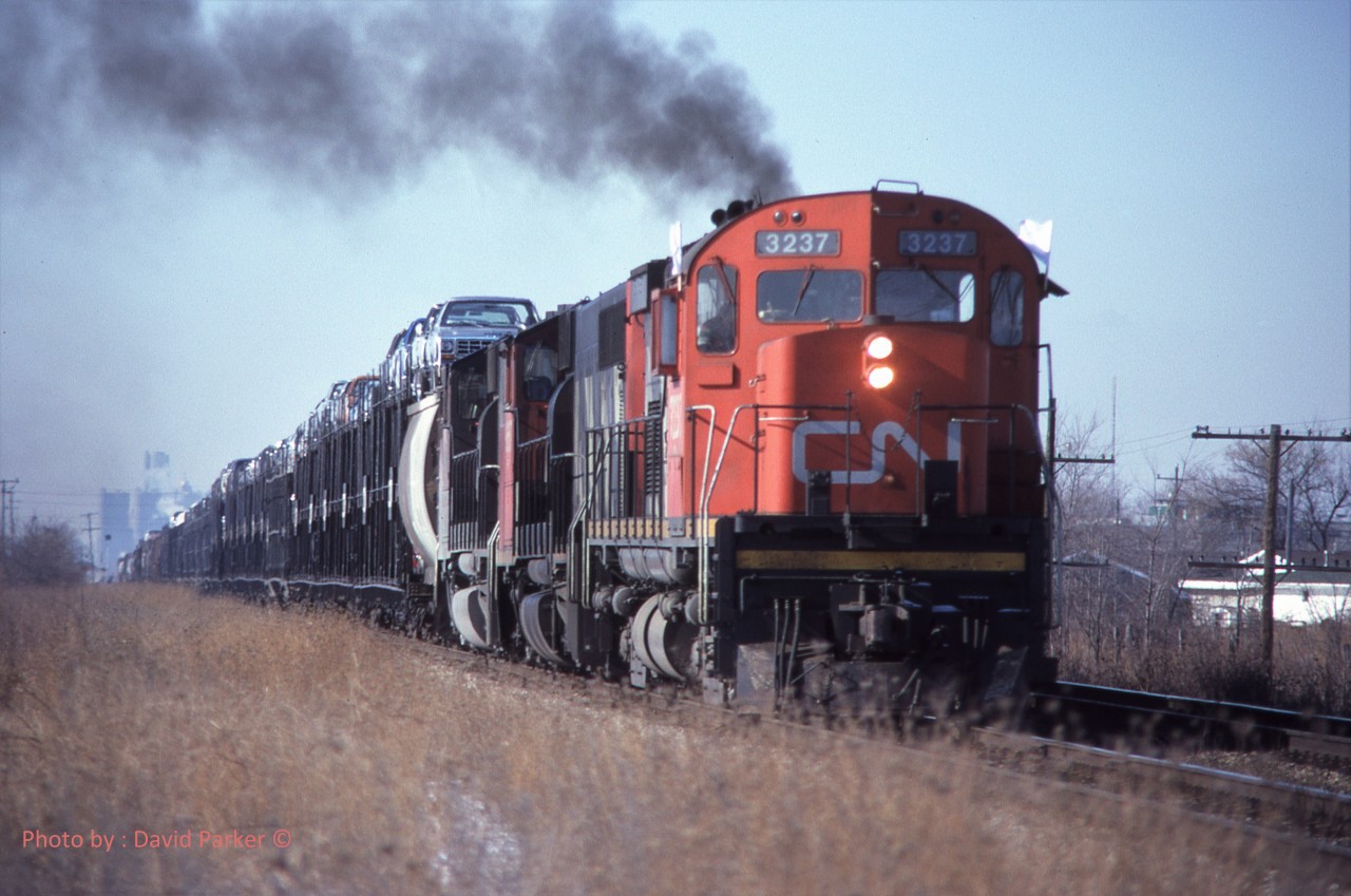 CN 3237-9667-9591 start train no. 422 away from Windsor with open multi-levels of Dodge pick-ups in tow.
