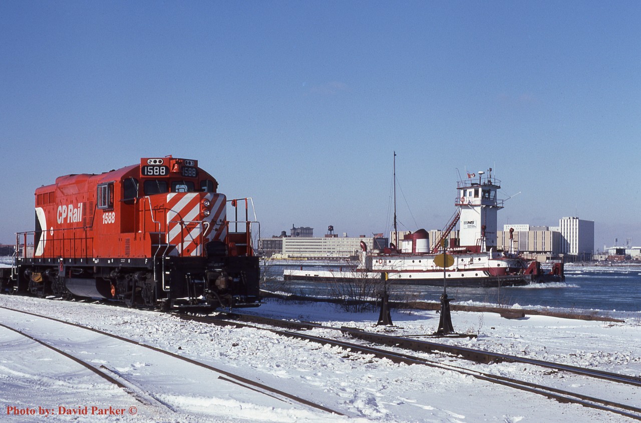 "South of the Border". CP 1588 is todays assigned Boat Job engine as NS tug 'R.G. Cassidy' heads light upriver to the CN dock. Across the river can be seen Detroit's Michigan Central Station, the US Post Office building and Tiger Stadium. Windsor, Ont. Dec 28th 1985.