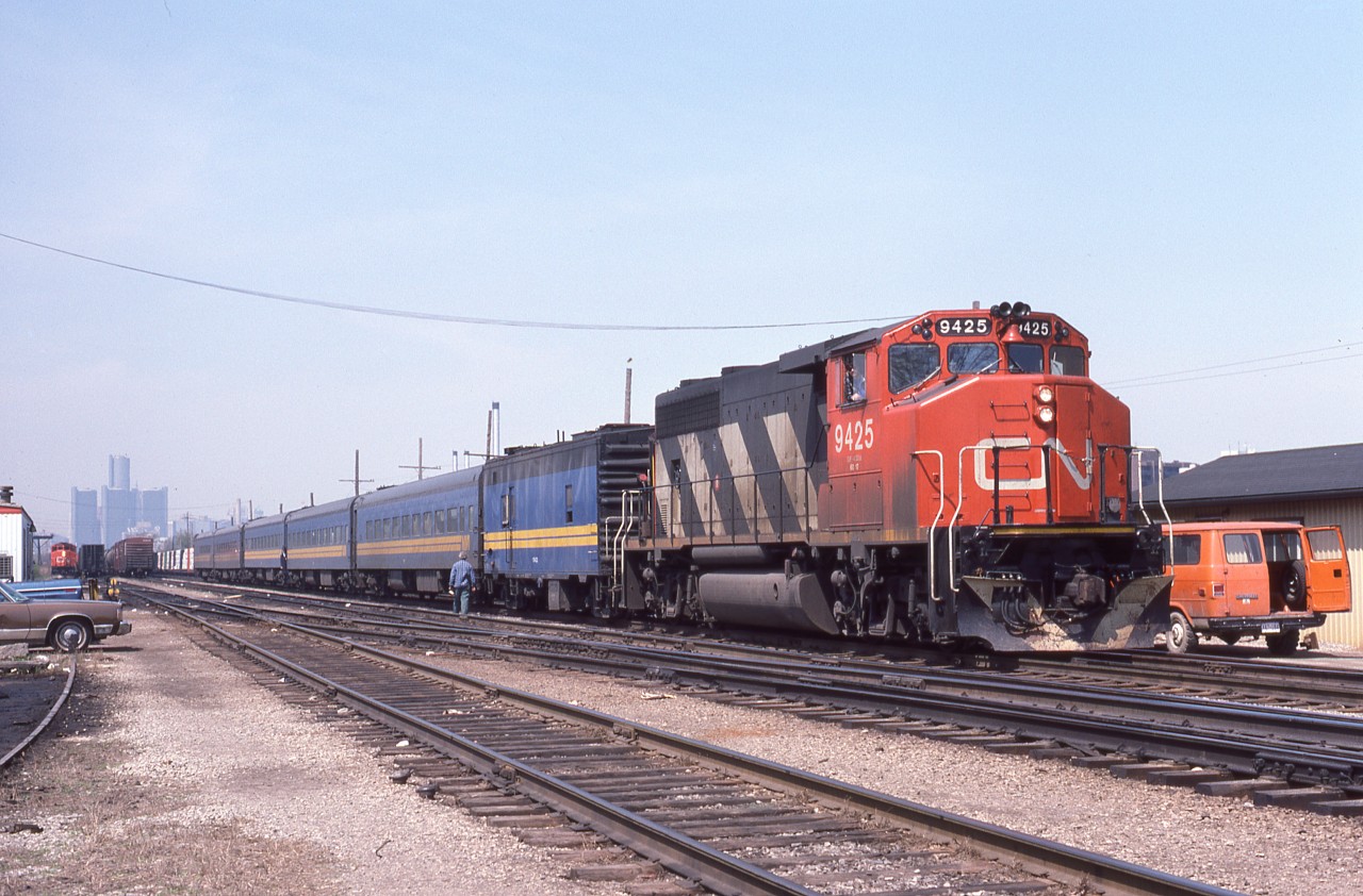 VIA No74 departs Windsor, Ont lead by CN 9425 with a steam generator car.  The employee on the ground appears to be ready to hand up some paperwork to the conductor in the vestibule of the second coach.  Probably not trainorders as they were picked up at Tecumseh. CN #422 lurks in the background ready to follow 74.