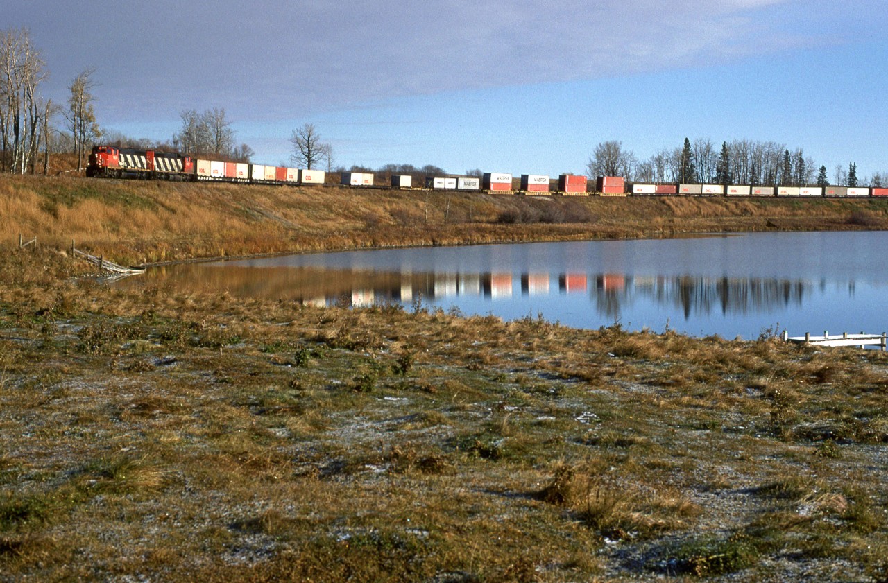 113, with a mixture of COFC and double stack containers swings through the first curve a Carvel as it rounds the north end of Mink Lake.