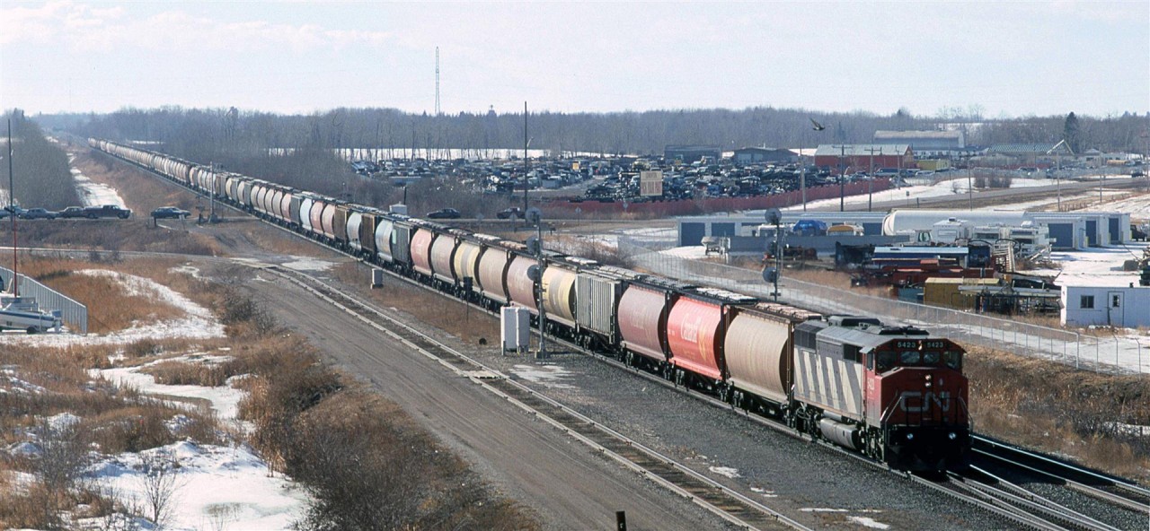This was a relatively common site on CN - an empty grain train of 100 hoppers, with only one locomotive to get the train over the line. CN's grades were not that significant, and they probably relied on the shop crews to keep their locomotives in fine working order.