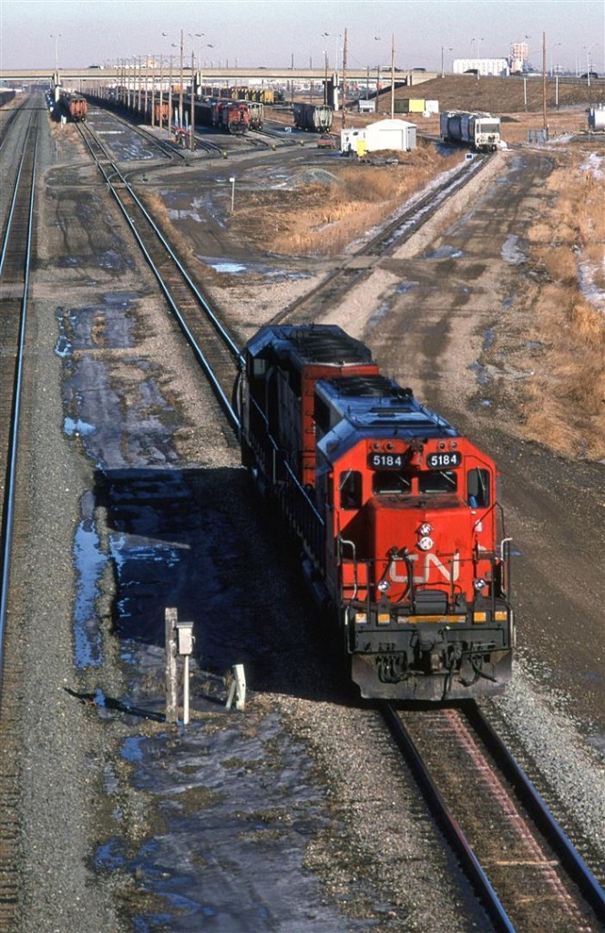 This is #813's power. Unfortunately, I did not note if it was coming off the shops or off the train for a power swap in Bissel Yard. The train is from Melville SK and is destined for Vancouver. 
I do have a photo taken a little later of a 813 leaving town with a different set of locomotives, but that could be a second section of 813.
In the background, the power for #785 readies its train for the trip west