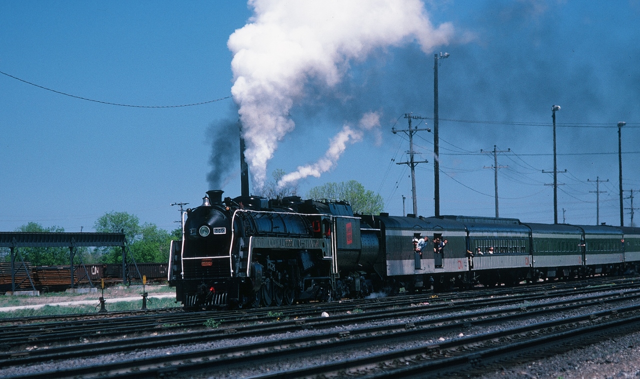 1977


    CN Belleville


   After a fast westbound run on the Kingston Sub, CN Extra* 6060 West pauses in the CN Belleville yard with more than a full head of steam ( * white markers no flags )


The Extra is en route to Toronto via the Kingston, Campbellford and Uxbridge Subdivisions 


May 7, 1977 Kodachrome by S. Danko



What's Interesting:


The Technical: Kodachrome ( ASA ) 64 transported by Nikkormat EL with Nikkor 135mm f2.8 telephoto lens 


The Vehicle: 1969 Pontiac Parisienne four door hard top (Oshawa build) Chevy powered 350 cu. in. V-8 with two barrel carb.


The Route: The Campbellford – Uxbridge Subdivisons – 'dark' territory -  back route was a favourite for many 6167 / 6218 excursions. To my knowledge this May 7, 1977 Extra was the only occasion that 6060 rode the Campbellford Subdivision – at the leisurely 40 m.p.h.  speed limit. Stations include Foxboro (mile 6.5), Madoc Jct.(12.2), Anson (mile 19.8 Jct. With Marmora Subdivision), Campbellford (30.9), Hastings (drawbridge at mile 42.0 ( the bridge is still in place)), Keene (53.7), Peterboro (CN spelling; drawbridge at mile 62.1 and interlocking with C.P. Rail at mile 63.0), Omemee (77.8) Lindsay, Manilla, Blackwater, Uxbridge, Goodwood, Stouffville, Markham, Hagerman, Scarborough Junction. 


The Extra: I believe this 6060 trip was a one way CRHA sponsored trip (a re-positioning)  consist included several Montreal open window commuter coaches and a Cafeteria. Perhaps some one out there may recall where this trip originated (Ottawa or Montreal). And how riders returned. Anyway it was mid afternoon, about 13:30 by the time the extra west appeared at Belleville.


The regular scheduled mainline class 1 steam: CN and CP Rail  and your Federal Government introduced the first VIA Timetable effective October 31, 1976 to April 23, 1977, at this time VIA was only a marketing campaign, each railway's passenger operations continued as independent divisions within CN and CP Rail – by 1978 CN passenger operations would be managed from the new VIA office – this would a profound impact on the CN Steam Program: summer 1978 VIA CN Timetable was the final year of the regular scheduled 6060 operation, appeared in the VIA CN 1977 and VIA CN 1978 Timetables ( and CN Timetables 1975 1976): 6060 Toronto – Niagara Falls ( and return) every Sunday and Wednesday months of July and August only.




More 6060 action


    on the Oakville Sub  


    on the Campbellford Sub  


    Road Switcher  


    on the Kingston Sub  


    on the Newmarket Sub   


sdfourty