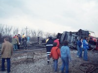 So I am standing on the Waterdown Rd bridge, quite a ways west of where I can dimly make out an approaching headlight. The sun is close to setting, I am losing light very quickly but figure before I go home I will wait this out and see what it is. Probably a passenger. As I watch the headlight coming at me, all of a sudden it appears to do a 'dipsy-doodle' and disappears. My scanner back then is still an under-dash Patrolman, fixed in the car, so I have no idea what is going on. So I go over to King Rd for a drive. There is the unit, CN 3102 laying on its' side. Passenger cars are fine, power has gone AWOL. The racket has attracted a small group of onlookers already, milling around like this was a flea market and someone was looking for perhaps a used chair. Remarkable, the lax security. Another age, another era. I wandered around for about 10 minutes, shooting pictures, most of them poor, as I had to hand-hold at 15th sec due to rapid loss of sunset light. This photo I picked up a board to use as a monopod. Not great, but it recorded the scene. No one hurt, as far as I know; and I never did find out what caused the unit to flip as it passed over King Rd grade crossing. 