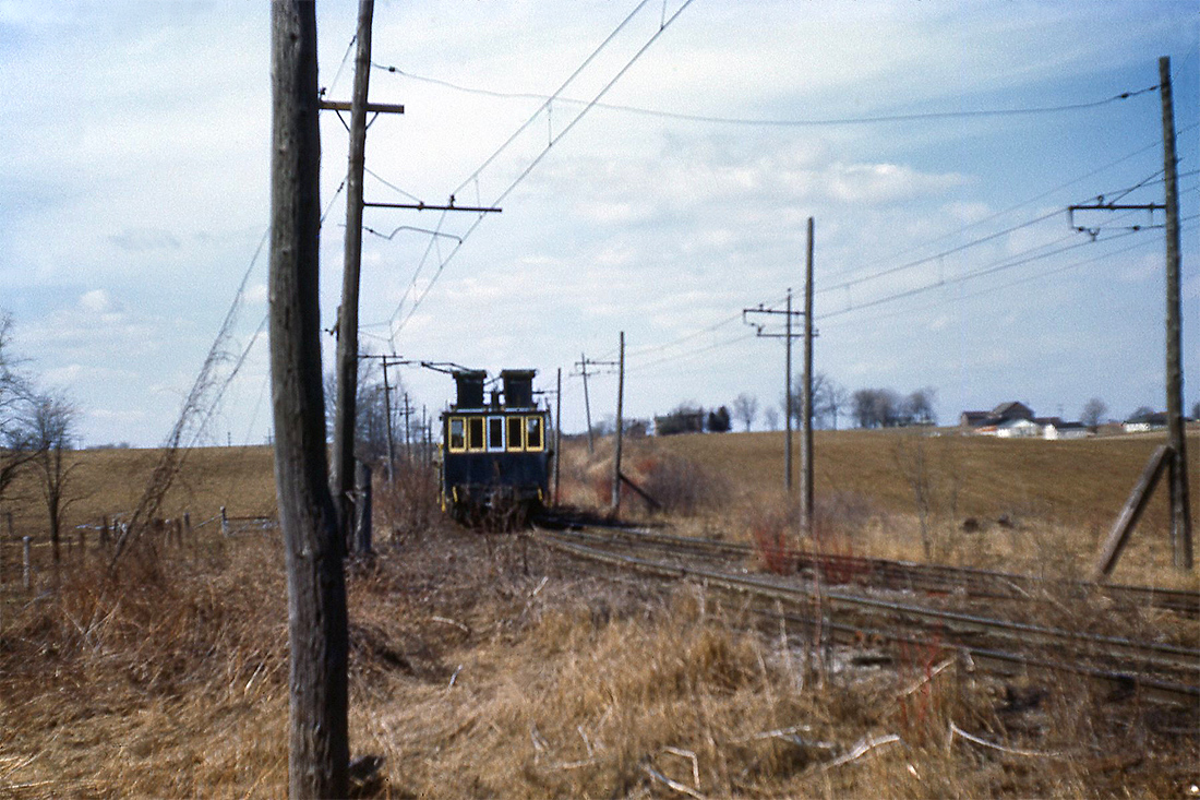 Another photo taken along the Canada Crushed Stone line that ran between the quarry north of Greensville and the dumper at Dundas, showing one of their electric dump motors traveling along the double-tracked section, and the overhead catenary that supplied power for electric operation on the line