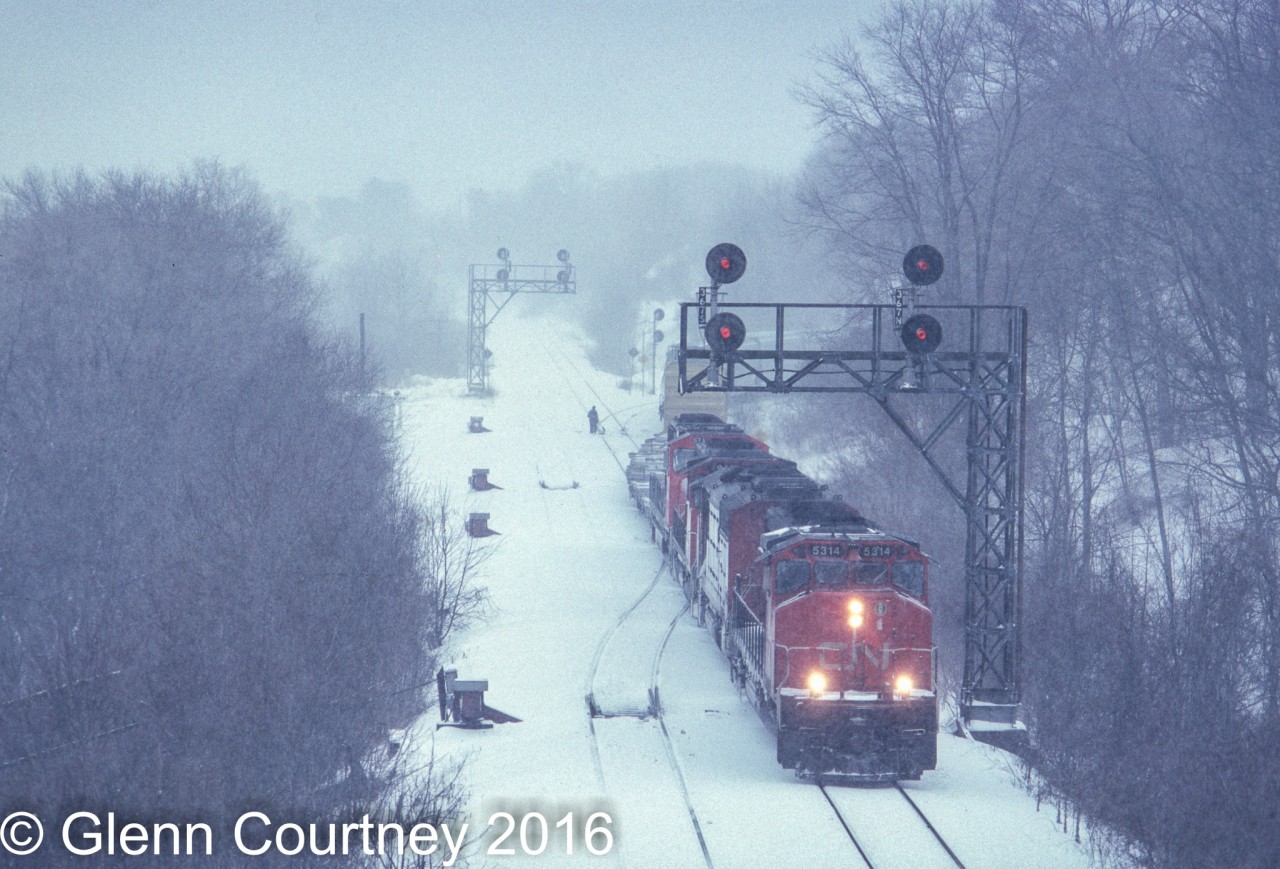 Before today's higher speed switches and triple track an eastbound led by SD40-2W 5314 rolls off the Dundas Sub and on to the Oakville while heavy snow falls. There's even a maintainer on hand to help keep the switches clear of snow.