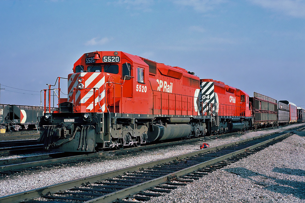 A westbound auto rack train with a pair of SD40s 5520 and 5504 as stopped for a crew change at CP's Agincourt yard. October 23, 1987.