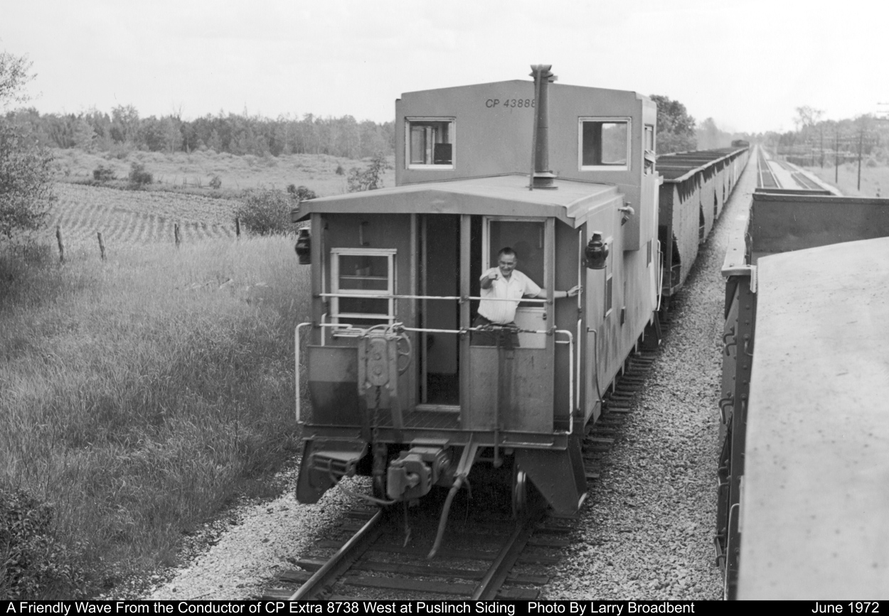 Conductor of CP Extra 8738 West gives a friendly Wave to the Guelph Jct Yard job as it passes them at Puslinch Siding  June 1972