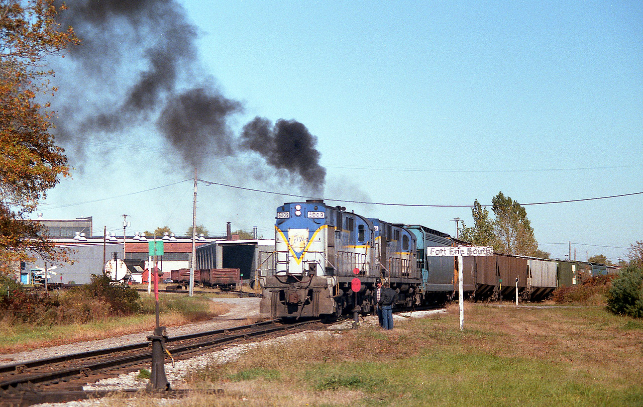 For D&H fans, this is about as exciting as it gets in Ontario. I was profoundly shocked to see on a nice warm afternoon in late October a pair of 'lightning stripes' roll off the International Bridge at Fort Erie. And doubly so when they proceeded to take the old 'Dunnville' line (gone now) which curved west along the south side of the CN shop area. This photo shows a mini-conference as I guess they wanted to make sure they knew what the procedure was, as this was a very rare move. I had never seen it before nor since. The transfer pulled down the Dunnville Sub in order to back the train around the Wye and into the yard for reasons I never did find out. Normally the transfers run directly into the yard, drop their train and then reverse up the next track to pick up traffic to take back to the States.  Not today. And a pair of old smokey 1961 era RS-11s!!!! This D&H fan from way back was in a state of advanced dribbling and drooling, I can tell you that!!!  For the record, power is D&H 5009 and 5005.
