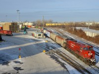 <b>Taking CP 112 apart.</b> CP 9358 is in the process of backing into Lachine IMS Yard with part of CP 112's train. At left is another part of CP 112, with DPU CP 8737 at the end of it. In the foreground at left an intermodal crane rumbles off into the distance on a crystal clear afternoon.