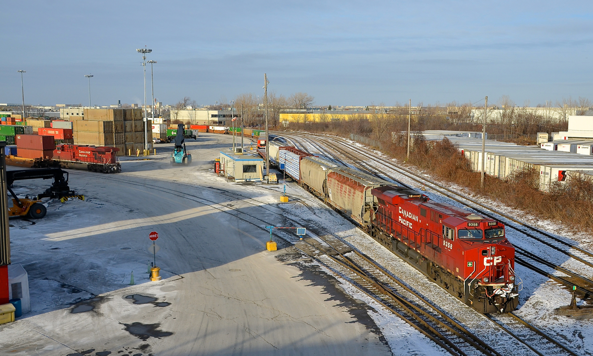 Taking CP 112 apart. CP 9358 is in the process of backing into Lachine IMS Yard with part of CP 112's train. At left is another part of CP 112, with DPU CP 8737 at the end of it. In the foreground at left an intermodal crane rumbles off into the distance on a crystal clear afternoon.