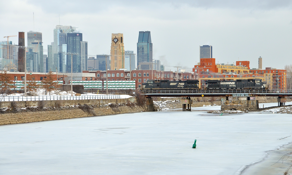A rare daylight CN 528 is crossing the frozen Lachine Canal with NS 9261 & NS 8411 as power. In the background is the skyline of downtown Montreal.