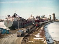 Egads!!  What a zoo down there.  Or so it looks, anyway. Couple of ships tied up for the winter adds to the busy scene; a long line of empty trucks making their way to the Sifto Salt company while a long string of salt loads is pulled out by Goderich-Exeter RR 4096 (in RailAmerica paint & RLK on cab) with leased HLCX 6522 behind. So much for snooping around down by the plant!! Because of the excessive grade up to the yard from the dock, heavy salt cars are brought up a few at a time and the southbound (for Stratford) train is assembled in the yard and then heads out. The making up of the salt train can keep the rail photographers occupied for a good length of time.