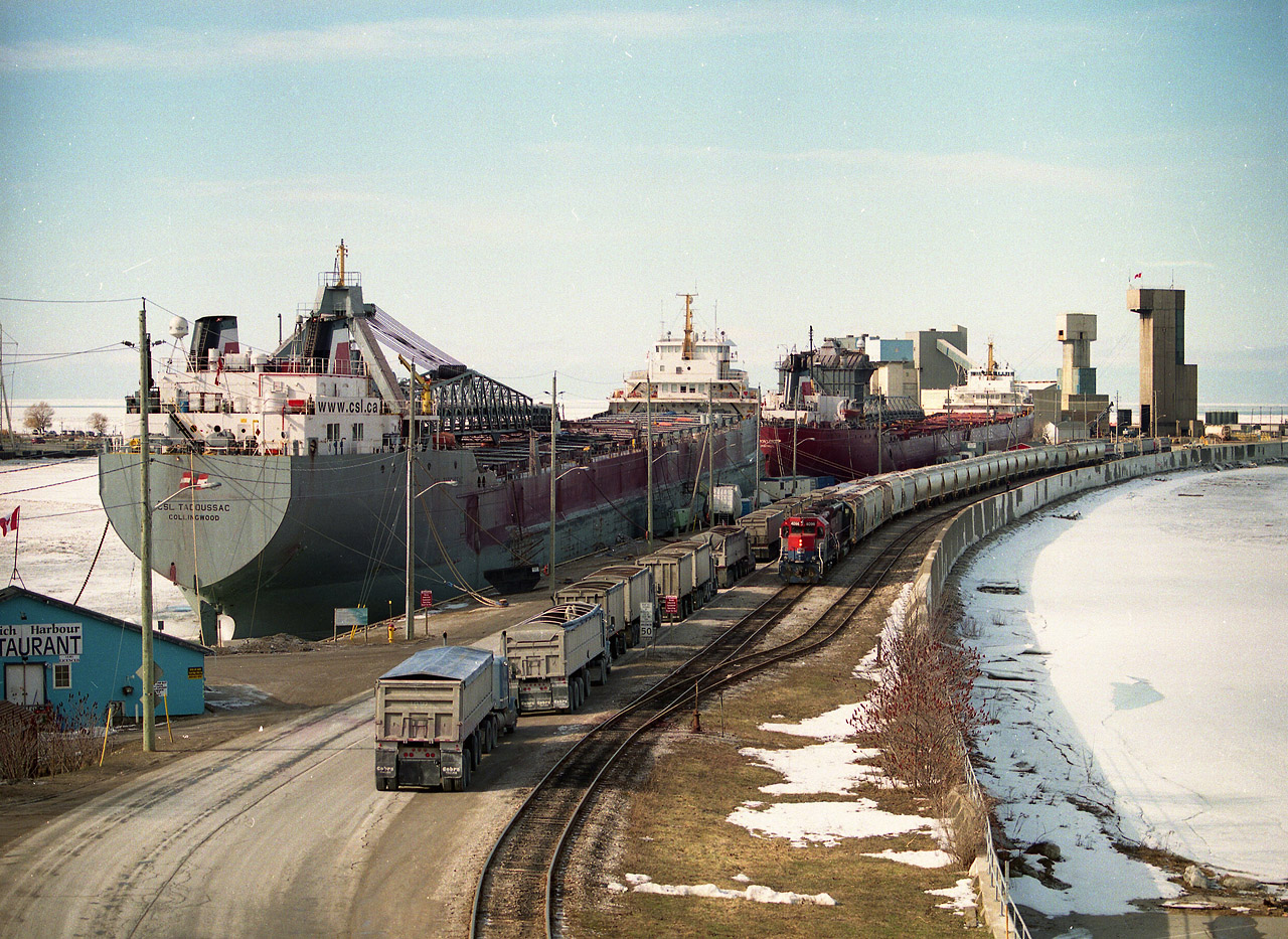 Egads!!  What a zoo down there.  Or so it looks, anyway. Couple of ships tied up for the winter adds to the busy scene; a long line of empty trucks making their way to the Sifto Salt company while a long string of salt loads is pulled out by Goderich-Exeter RR 4096 (in RailAmerica paint & RLK on cab) with leased HLCX 6522 behind. So much for snooping around down by the plant!! Because of the excessive grade up to the yard from the dock, heavy salt cars are brought up a few at a time and the southbound (for Stratford) train is assembled in the yard and then heads out. The making up of the salt train can keep the rail photographers occupied for a good length of time.