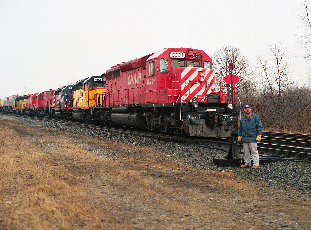 Rather colourful lashup on the head end of this Toronto-bound #521. Appropriate, because engineer Gordie Rivers was not long off retirement, and so he posed (pre-arranged) for his 'official' portrait at the Mile 4 switch at the entrance to the long-gone Montrose Yard. Power is CP 5591, HATX 402, HLCX 3111, CP 4206, 5939, and HATX 401.