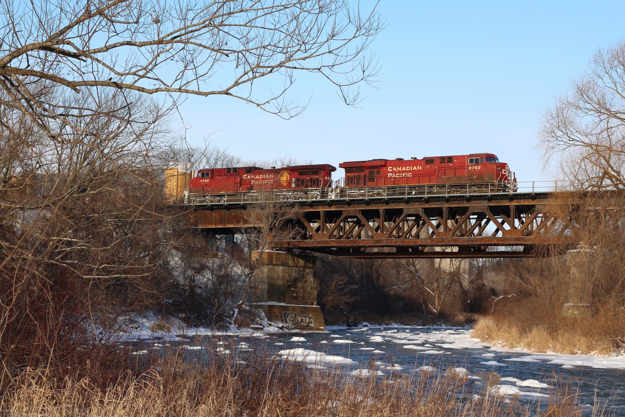 Canadian Pacific's bridge over the Credit River reveals a little history in the morning light, its piers were originally built by the Credit Valley Railroad to support a single track mainline. Later the second main was added but the new addition to the old pier was simply formed concrete instead of stone, and the newer truss didn't totally match the original design either. Here an eastbound with a pair of GE built locomotives thunder across the bridge on their way to Toronto yard.