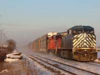 A combination of snow being swept off the ground and snow being lifted off the roofs of the auto racks by the strong wind cover the roadbed in the background as train 147 storms westward out of the dip at Hornby.