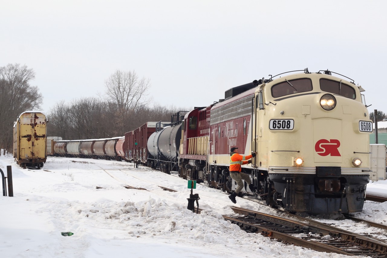 A couple of OSR vintage locomotives in corporate colours have just finished reassembling their train after lifting cars in Ingersol yard. The brakeman is climbing aboard, and in a few minutes the train will resume its journey to the CP interchange in Woodstock.