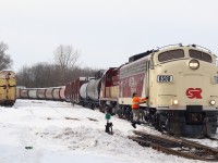 A couple of OSR vintage locomotives in corporate colours have just finished reassembling their train after lifting cars in Ingersol yard. The brakeman is climbing aboard, and in a few minutes the train will resume its journey to the CP interchange in Woodstock.