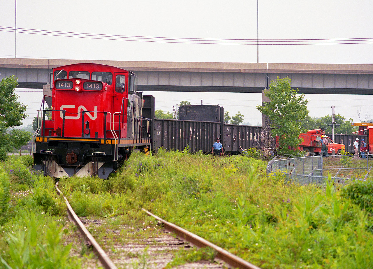 CN 1413's train derailed crossing Dieppe Rd in North St. Catharines and in this photo we see workers arriving on location at the crossing and assessing the situation. We also see a Niagara police officer doing his nonchalant assessment as well, and I waited to see what activity was going to transpire here, while waiting for him to saunter up to me and tell me to clear out. He did. But he was very polite about it. This trackage is no longer, having been lifted quite a few years back.  There was no more industry left in the city north of the Skyway Bridge (pictured)to service. A steel supply company just out of sight in this photo by Bunting Rd/Eastchester is now as far as this line goes.