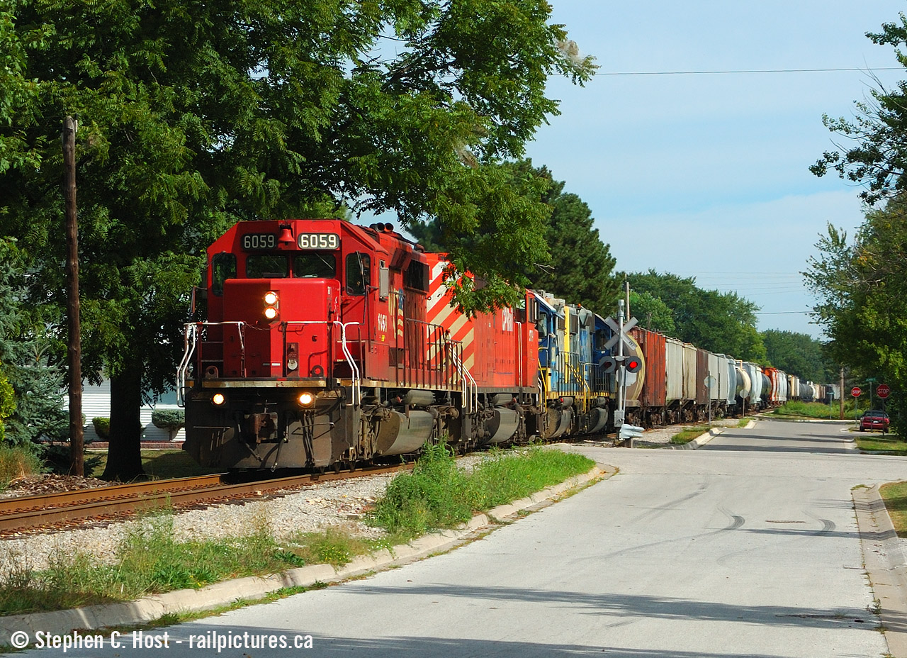 My oldies again  On track now abandoned, Port Lambton Ontario sees an 83 car train running alongside MacDonald Street with four locomotives back in August 2005. The CP Locomotives were run-thru power as CP took the train from Chatham to Detroit (CP 525/524) where CSX would resume the journey to Toledo over their own rails. D725 ran five days a week (Monday-Saturday) and began their day in Sarnia at 0500. The two CSX Locomotives would be dropped off in Chatham for a Blenheim turn (Chatham to Blenheim, back to Sarnia) which ran two days a week (Tues/Thurs) and I did take the time to follow. Question for those who know:a) What happened to CP 6059 and 9019?
