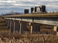 <b>The Tunnel Bridge.</b> At mile 4.2 of the Trillium Canal Spur, an ex-Canadian Pacific MLW RS18u guides a single car from Feeder Yard across the "Tunnel Bridge" for St, Catharines. Once operated by the Canadian National, the tunnel bridge spans a deep cut, wherein Canadian Pacific's Hamilton Subdivision runs on the approach to a tunnel underneath the Welland Canal. During the early 1970s, the Niagara Region saw a major reconfiguration of its railroad lines with the advent of the Welland Canal bypass project. On this sunny December morning, TRRY 1859 is seen working its way towards Welland and ultimately St. Catharines, while the 108 spots cars at the Atlantic Biodiesel facility in the background. Later in the day, the 108 would also cross the Tunnel Bridge to access the small Trillium yard in Welland. Once upon a time, Canadian National and Norfolk Southern shared an intermodal facility on the 108 side of the Tunnel Bridge in Dain City. Like so much of the infrastructure in the area, though, it is all but a memory.