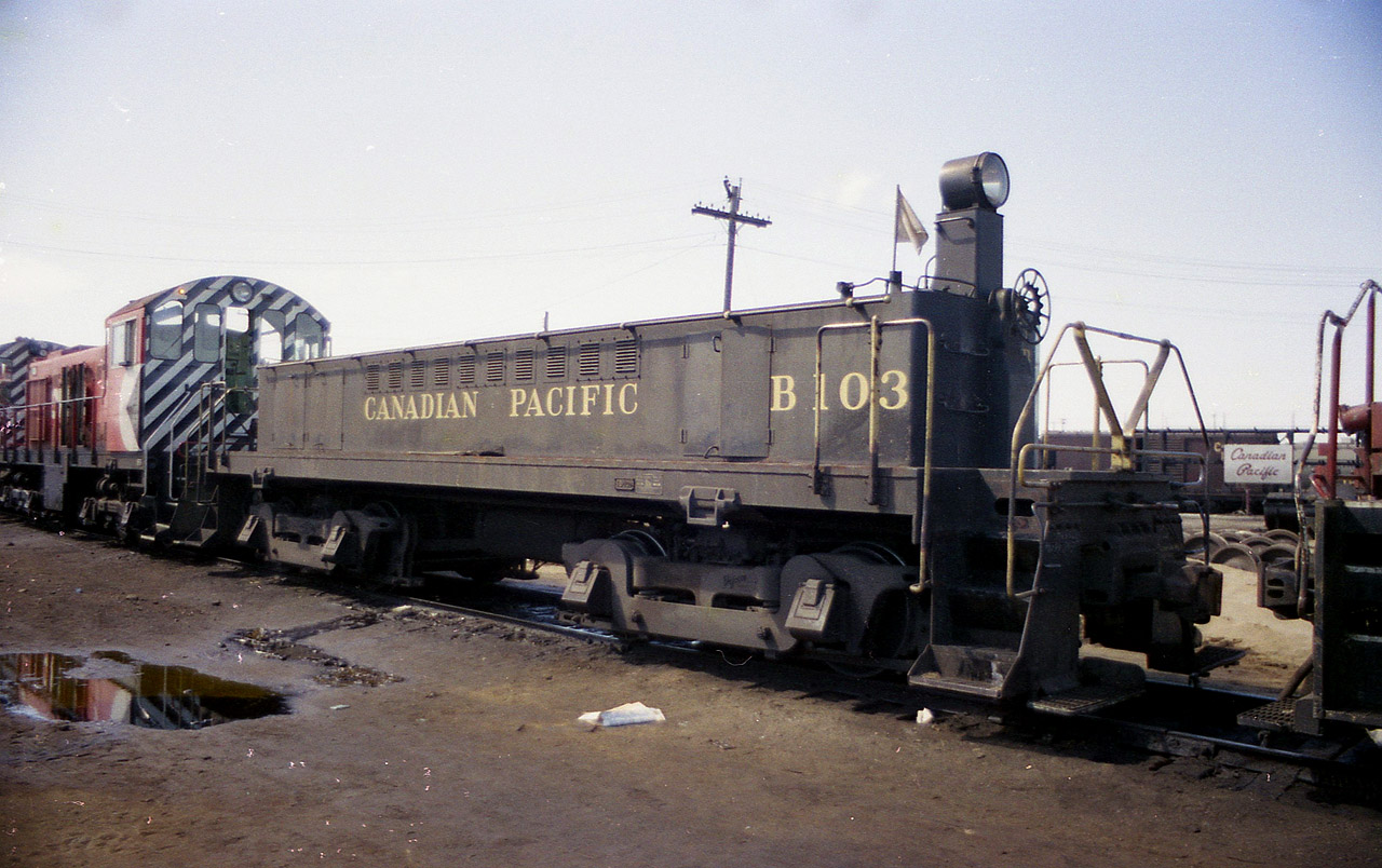 Not your average 'B' unit. This motorized booster is one of only 4 built by MLW. B100 & B101 were built in  1951. Booster unit control locos converted to mother these units were CP 7033,7038 and 7039. Then boosters B102 and B103 (shown) were built in 1957 and three more MLW S-2 switchers were converted for use with these: 7081, 7082 and 7083. In 1966 two more switchers were done...7030 and 7040. All units retired now, (B101 converted to a scale test car) the B103 being the last to die, back in 1984. Unfortunately I did not record the number of the switcher(s) shown. I keep wondering if that puddle in the foreground is oil. Probably not, but many yards were extremely contaminated back then.