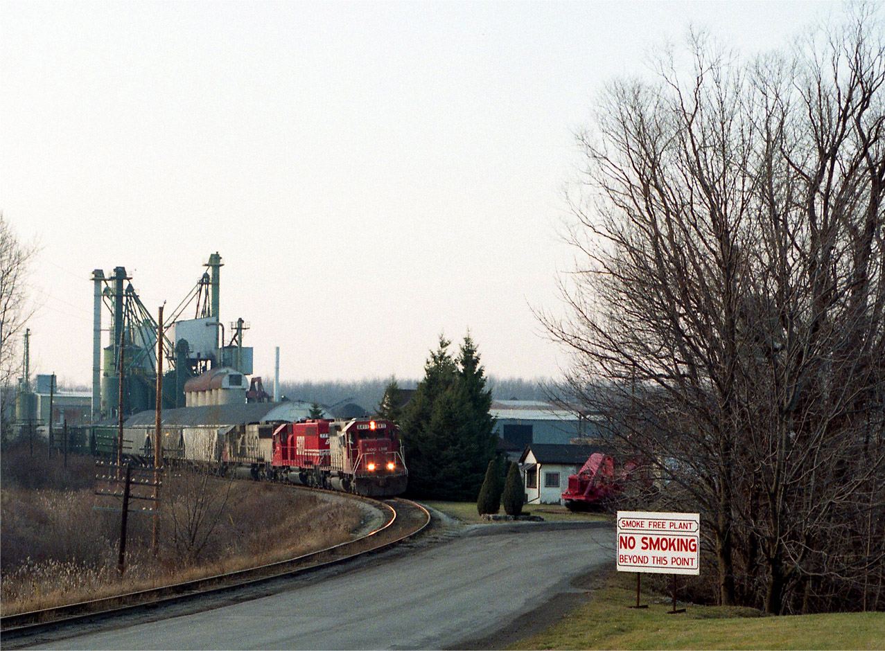 Grain Train!!  Always nice to see, but alas, this was 25 years ago; and now they all seem to run Stateside or around the Lakehead. It has been a long while since I have seen one thru Niagara. Here is an all-SOO lashup; SOO 6411, 779 and 6013 passing the old Waterdown station, now offices of the SunOPTA Minerals Inc company which is on Parkside Drive in North Waterdown. This train probably ran thru to the Port of Albany, NY. Dispositions: SOO 6013 went to Indiana RR in 2006. SOO 6411 (became CP) went to DME in 2000. SOO 779 (became CP) retired.