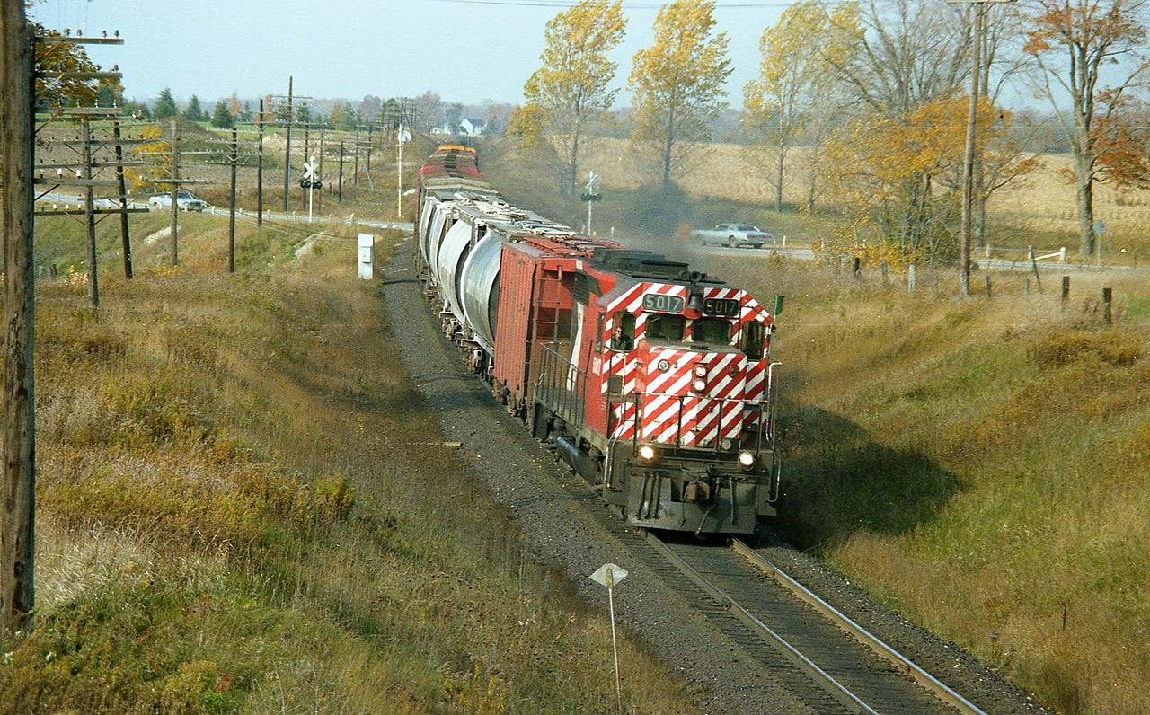 Beautiful windy fall day out there as local CP 5017 (GP35) heads into Woodstock eastward with a short train. The train is crossing Hwy 2, which certainly doesn't look like a provincial highway, seeing such minimal protection at the crossing ........and this location is somewhat obscured when approaching from the west due to a dip in the roadway.  I am standing on a farm laneway overpass, an old wooden structure that serves about 3 farmhouses. This particular bridge was replaced by a modern steel one a few years ago. I very rarely shoot here as it IS private property. Pleasant local citizens, thankfully.