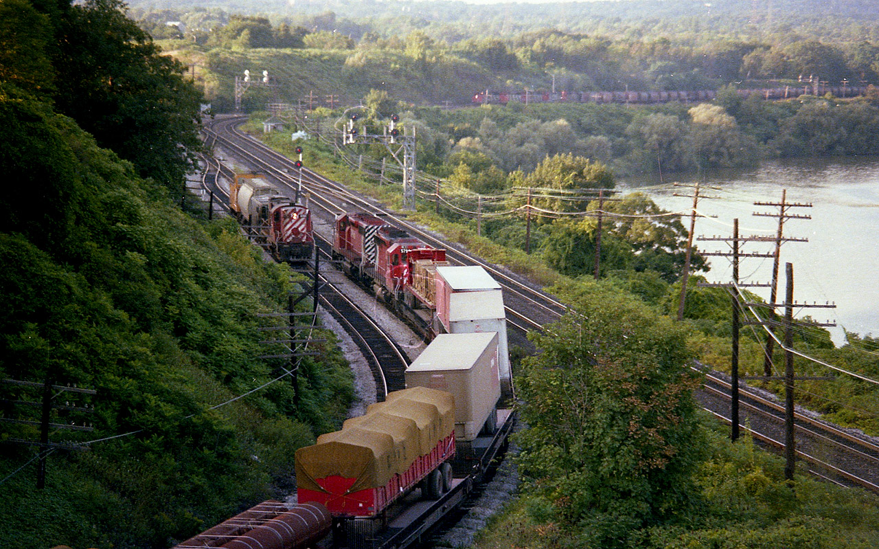 Action Central!!! Yep. Thats what it was like around Bayview during the dinner hour some years ago. Behind me the CN local was working the Hamilton Stuart St yard, the Budds for Niagara had just passed, as had the GO running east with 902/706. And I happened to be in the right spot because I heard the "Goderich" coming down from Waterdown so zipped over to the High Level bridge from Bayview to grab a shot of it. To my surprise, out comes the TH&B Starlite, with CP 5699 and 5790. As CP 8756 passes heading into Aberdeen, the Starlite, which runs to Toronto via the CN, has to wait because here comes the Dofasco Ore train! A couple of passengers up and down the Dundas Hill as well as a freight further complicated this rather productive hour. Sure do not experience days like this any more. Ore train power is: CN 9550, 9582, 9453, 4006 and 5045.
