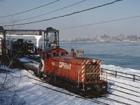 On March 5, 1978, CP SW8 #6703 is loading the N&W barge Windsor at the ferry slip in Windsor, Ont. Notice that all of the cars are excess height auto racks.  The ferry service was only used for cars that couldn’t fit through the tunnel.  When the larger tunnel was completed in 1994, the ferry service was stopped.  The yard and slip are now a park.  The barge Windsor was owned by the N&W and was originally built in Toledo in 1930 as a steam ferry for the Wabash. It was converted to a barge by the N&W in 1969. Internet reports show it being scrapped at Port Colborne in 2007.