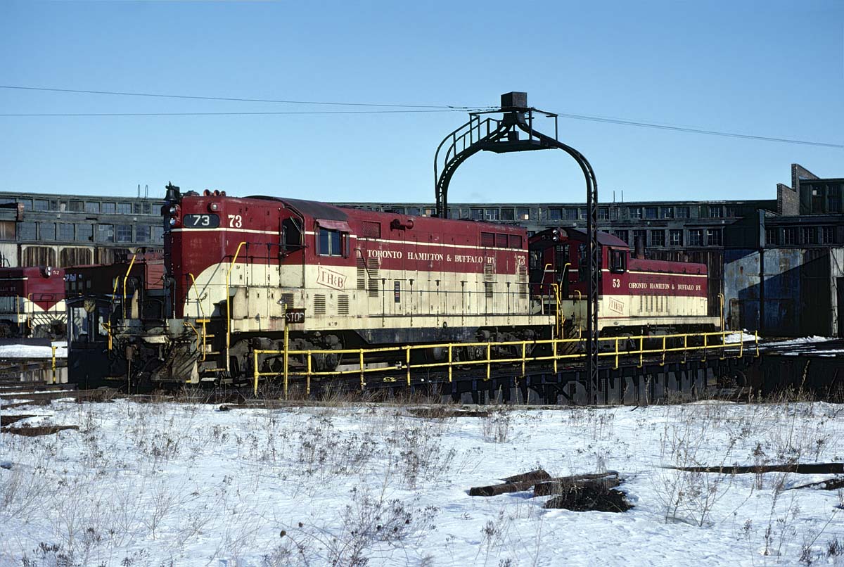 TH&B GP-7 #73 and NW-2 #53 share a ride on the Chatham Street turntable on February 28, 1982.  Both units wear the road's attractive cream and maroon paint that the first diesels delivered in 1948 wore.  #53 was part of that order. The TH&B is one of the few roads to keep a consistent diesel paint scheme for such a  long run (1948 - 1987)