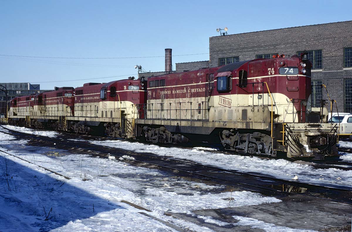The power for a unit train down to Port Maitland sits on the ready track at the Chatham Street roundhouse on the morning of February 28, 1982. We'd be a little disappointed that they spoiled the solid lash-up with a trailing CP MLW but a bigger disappointment was that the clera skies didn't hold up long enough.