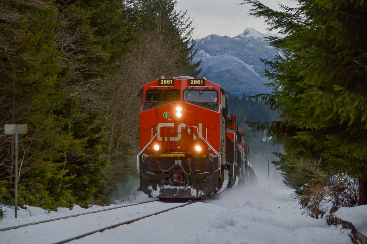 571 was an interesting train on New Years Day 2017. After the crew arrived to work in Squamish, they got on their power (CN 2861 and 8816) and coupled to 546, which incidentally had just arrived a few hours earlier BCR 4610 in the lead position. The railfans of Squamish held their breath as the crew discussed putting their power in the lead, or that of 546, which would have meant a BCR unit leading a train in her home territory twelve and a half years after the provincial carrier was absorbed into CN. 
After much debate, the crew settled on 2861 to do the honours. Too bad. After that, 571 started their work in the yard, and we left the yard for Brackendale, as we knew the train would soon depart Squamish for Lillooet.  Seen in this shot is 571 kicking up a snowsquall as it picks up speed on the straightaway in Brackendale. Today's train was light, a mere 1600 feet, consisting of 21 empty gondolas bound for the copper loadout at Gibraltar near Williams Lake.