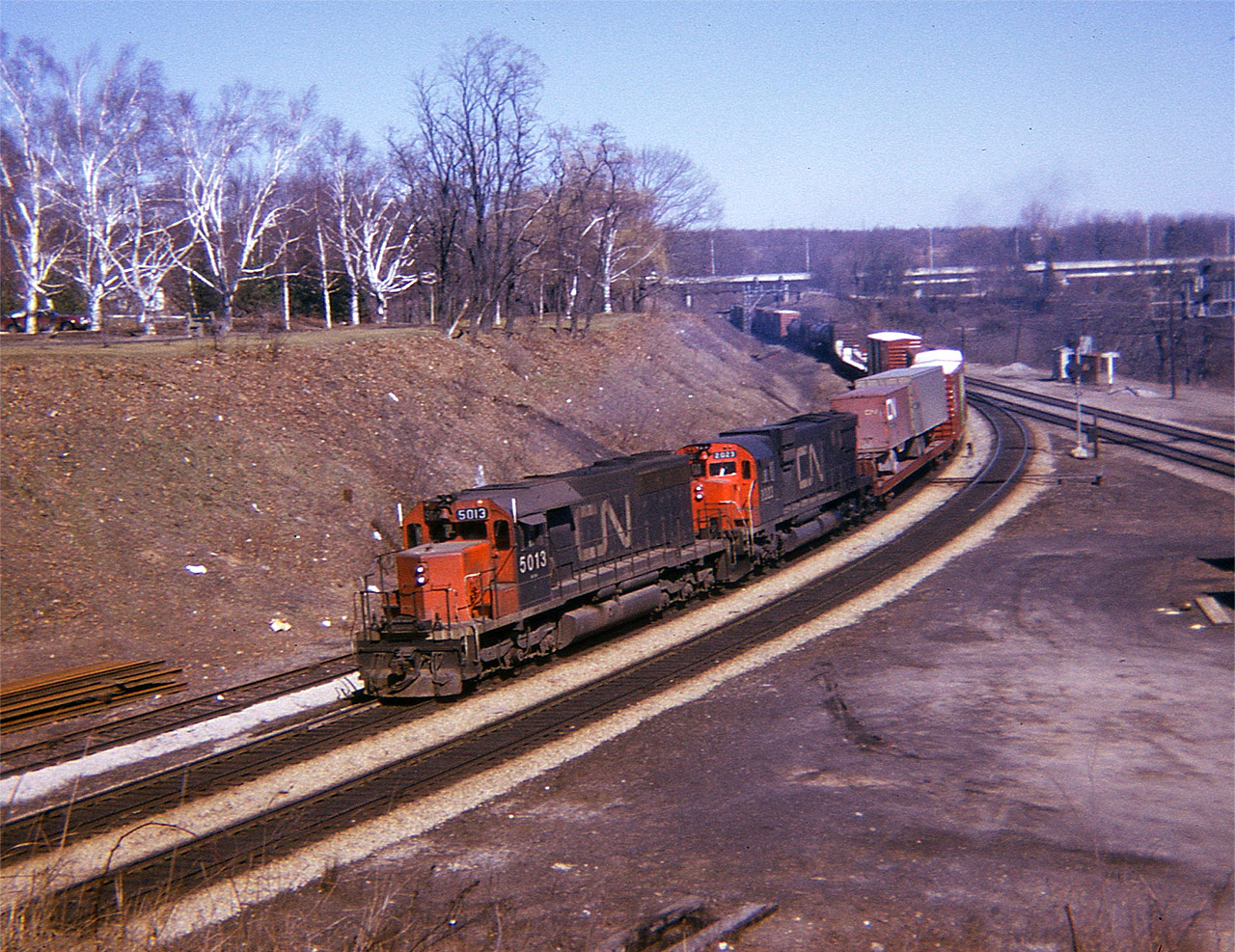 Basic Bayview:  To start off the New Year 2017 offered up here is a basic shot of Bayview Junction as it would appear back in the pre-spring days of 1974. Open and barren. CN 5013 and 2023 are pulling a westbound around the bend, I think back then speed restrictions to 15 MPH, but have forgotten. The 'third' track is still intact; the old location in which engines back in the steam days waited to assist the westbounds up the long 9 mile grade thru Copetown. It is now just a stub, used by MoW, note track stored there. One thing that has not changed over the years is the abundance of litter, the melting snows leave so much to be undesired each spring.