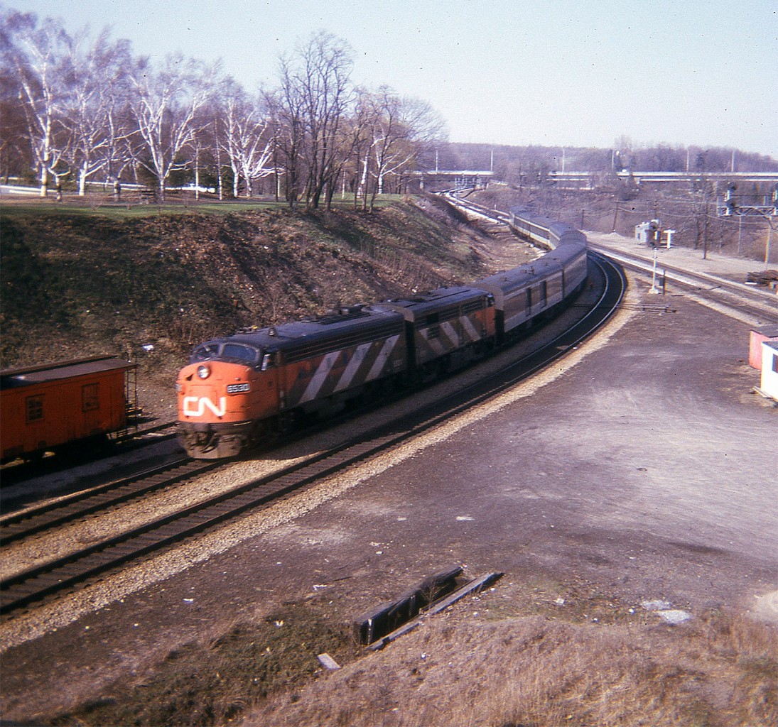 Late April, the leaves are just beginning; and I am up on the hillside enjoying the day. It is mid-afternoon by the looks of it, and in this pre-VIA image, CN 6530 and 6527 take a westbound passenger towards Copetown Hill and London.  There are various cars on the stub track behind the loco, as well as an old wooden CN caboose, partly visible on the extreme left. Adds a bit of "age" to the photo.