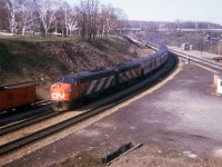Late April, the leaves are just beginning; and I am up on the hillside enjoying the day. It is mid-afternoon by the looks of it, and in this pre-VIA image, CN 6530 and 6527 take a westbound passenger towards Copetown Hill and London. There are various cars on the stub track behind the loco, as well as an old wooden CN caboose, partly visible on the extreme left. Adds a bit of "age" to the photo.